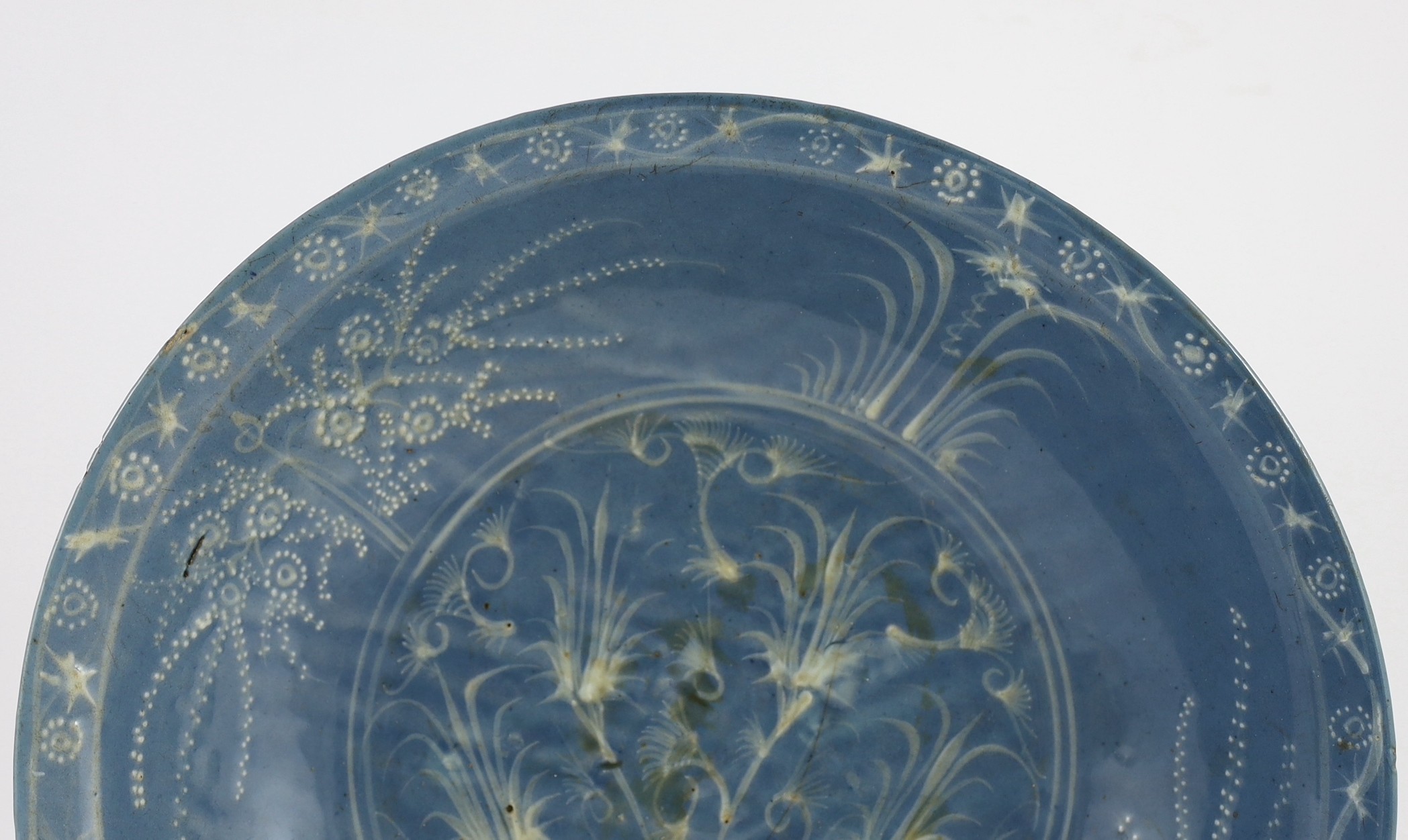 A Chinese Swatow slip-decorated blue glazed deep dish, Zhangzhou kilns, early 17th century, 38cm wide, crack to base